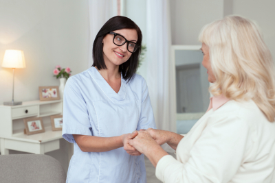 female caregiver wearing glasses while taking elder woman hands