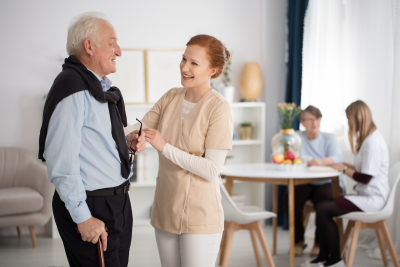 Tender attention of medical staff towards elderly men and woman comforting in luxury care facility common room